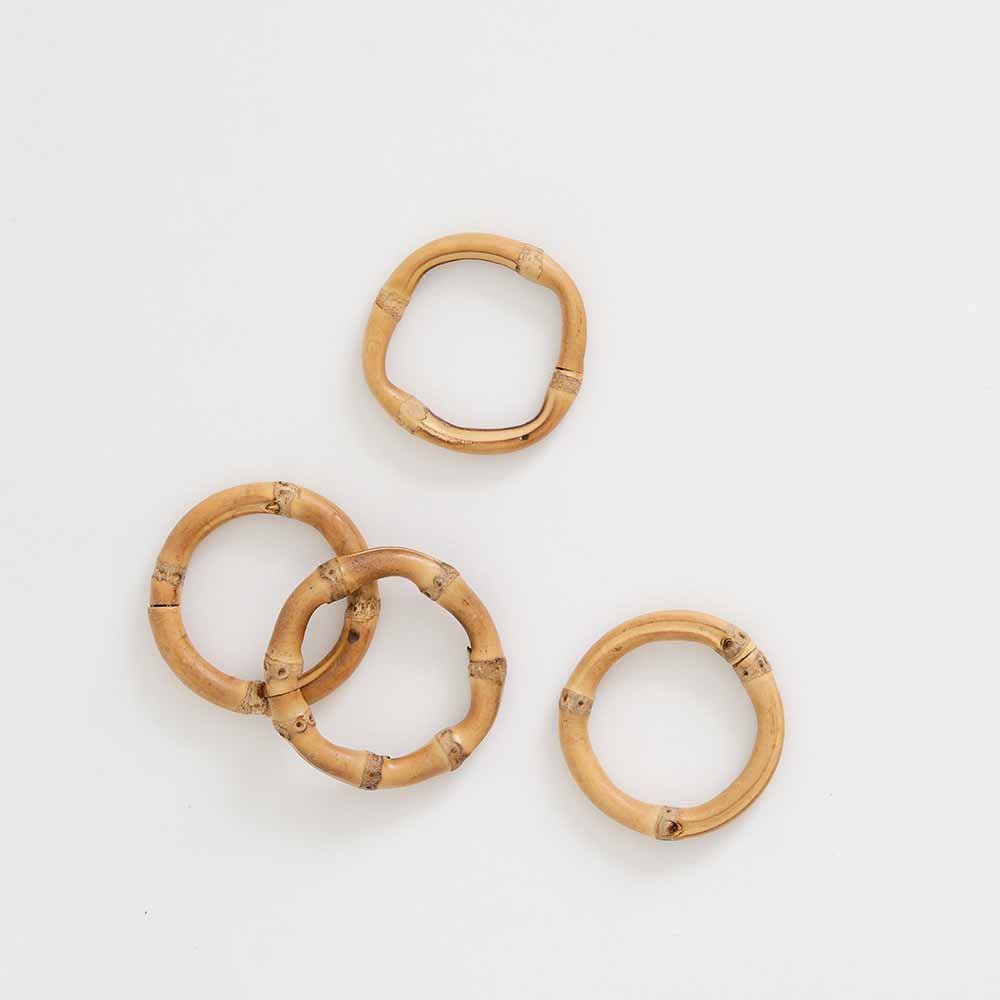 Set of four round bamboo napkin rings from Pomegranate, natural wood finish for elegant table linens and dining decor.