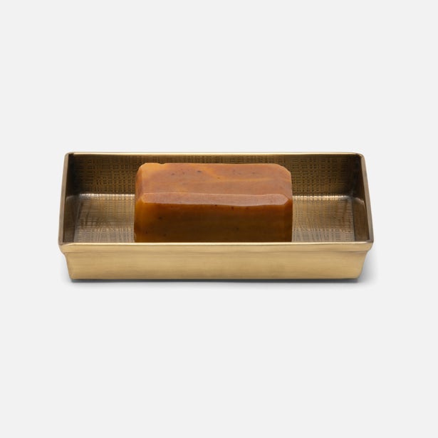 Brass soap dish with a bar of soap on a white background