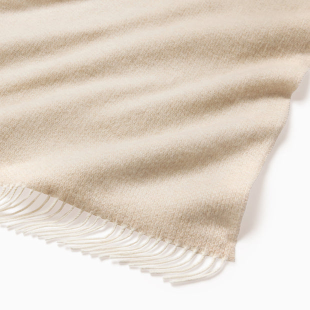 Beige Sferra Cervino throw blanket with soft, luxurious fabric and woven texture, draped elegantly.