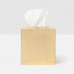 Gold tissue box with a white tissue on a light gray background