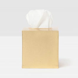 Gold tissue box with a white tissue on a light gray background