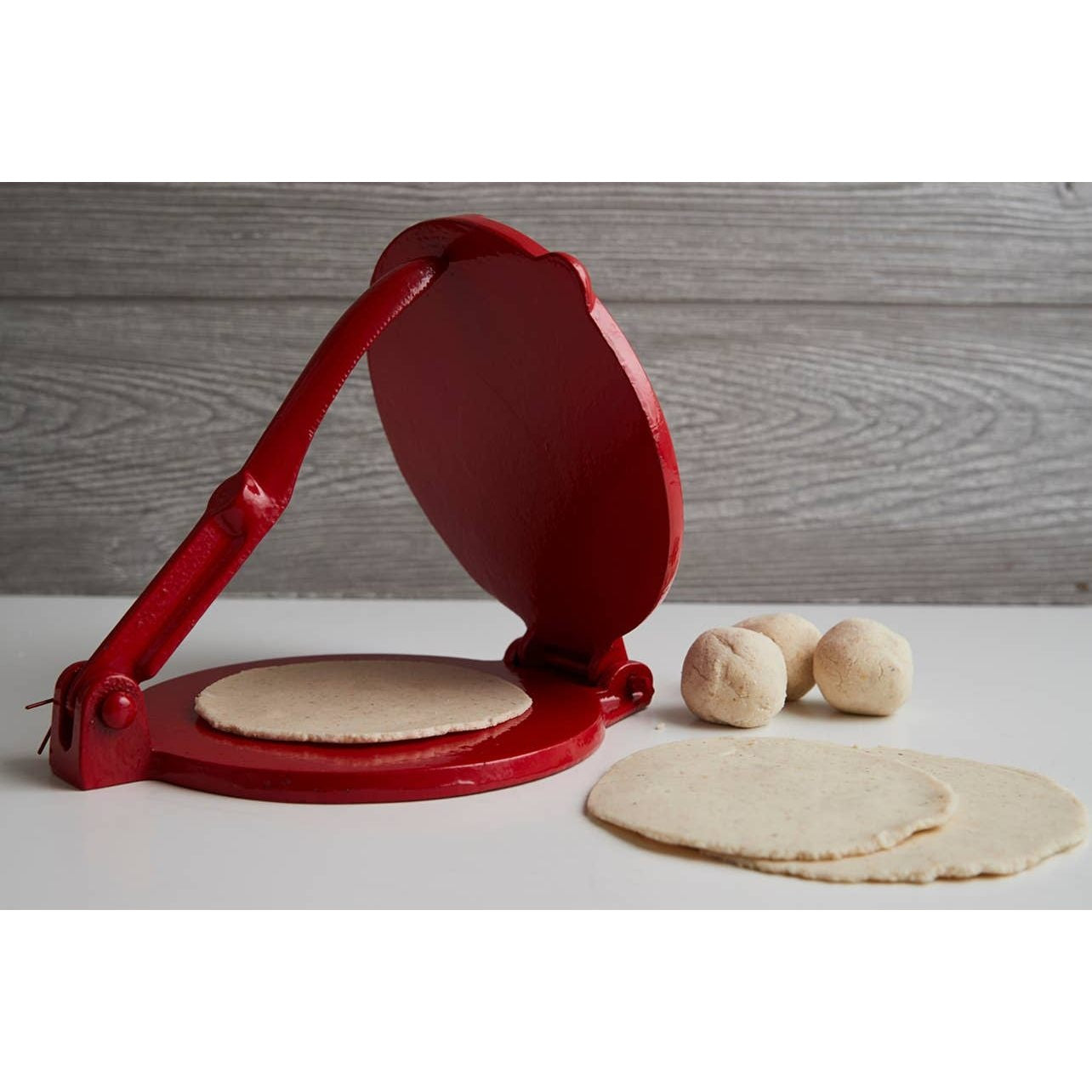 Cast iron tortilla press kit by Verve Culture showing a sturdy cast iron tortilla press with wooden handles on a wooden surface.