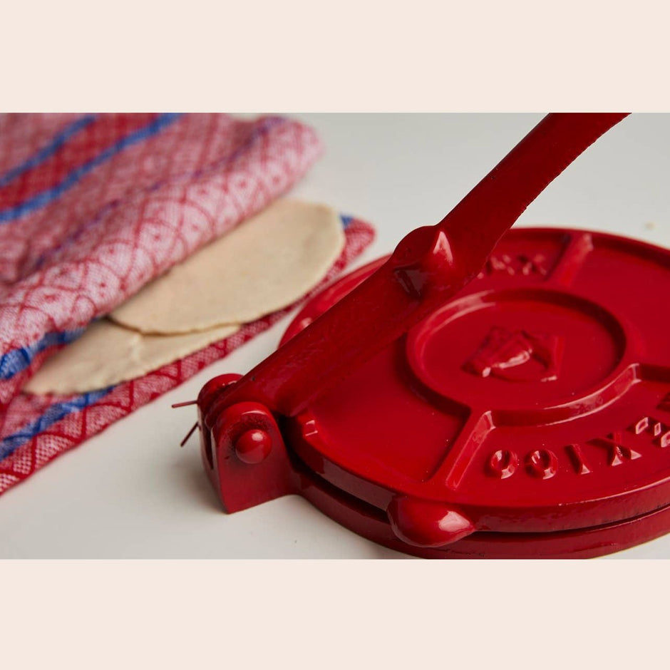 Cast iron tortilla press by Verve Culture with wooden handles and included tortilla maker accessories.